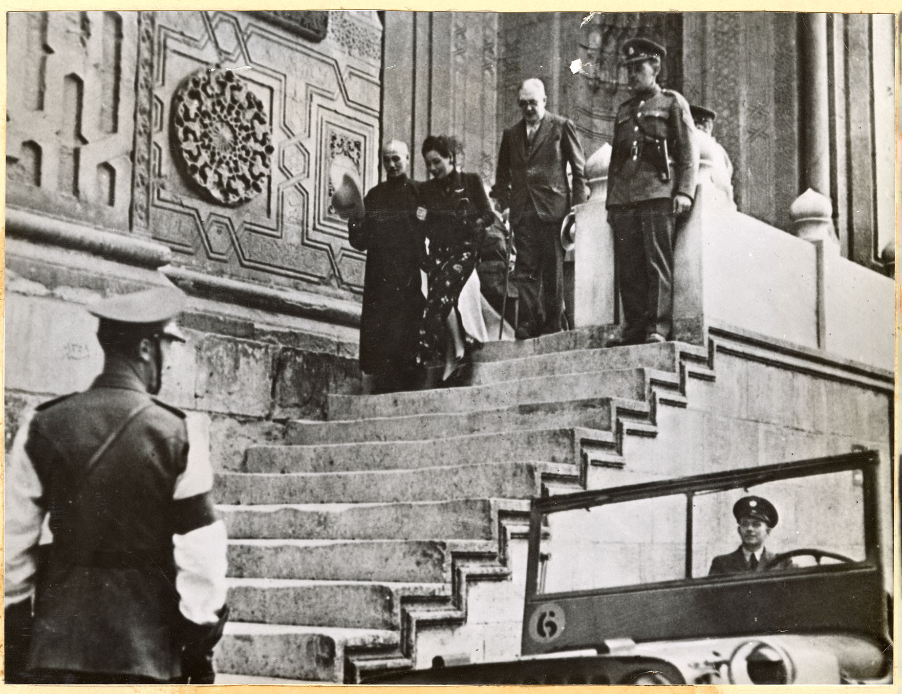 Chiang Kai Shek and his wife descend a staircase while other officers wait Chiang Kai Shek and his wife descend a staircase while other officers wait
